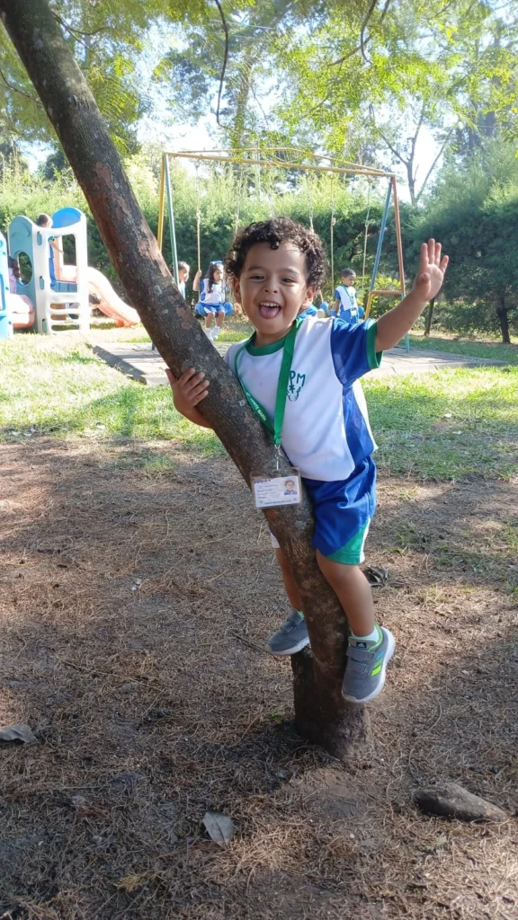 Niño abrazando árbol y saludando